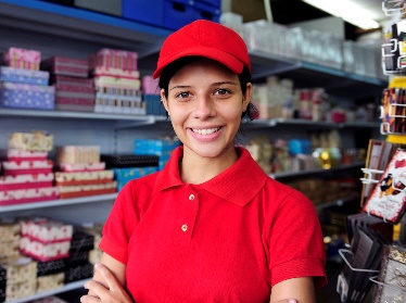 A young person working in a gift shop. They are smiling.
