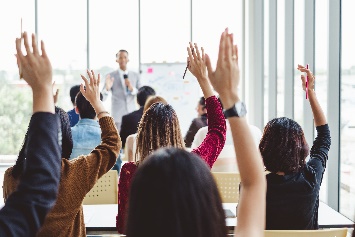 A group of people in a meeting with their hands raised.